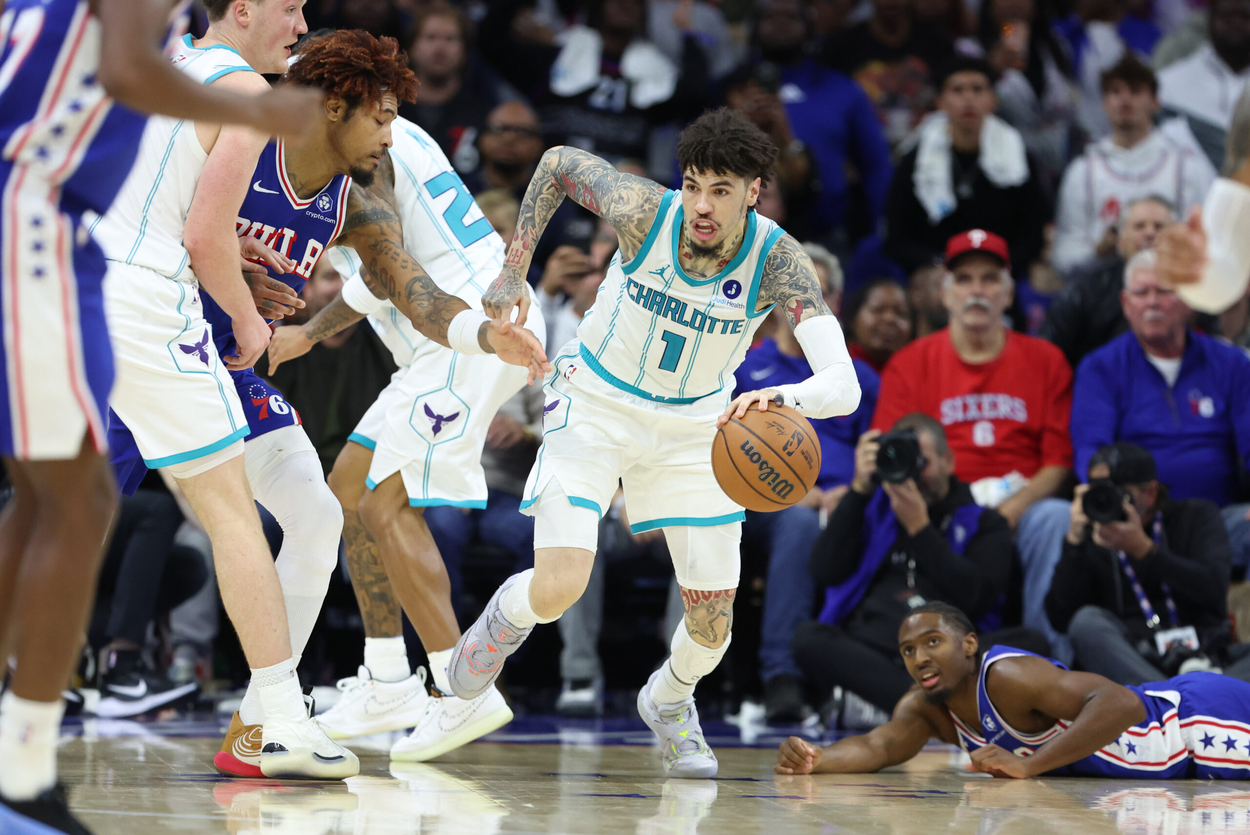 Oct 25, 2025; Philadelphia, Pennsylvania, USA; Charlotte Hornets guard LaMelo Ball (1) controls the ball between Philadelphia 76ers guard Tyrese Maxey (0) and guard Kelly Oubre Jr. (9) during the fourth quarter at Xfinity Mobile Arena. Mandatory Credit: Bill Streicher-Imagn Images