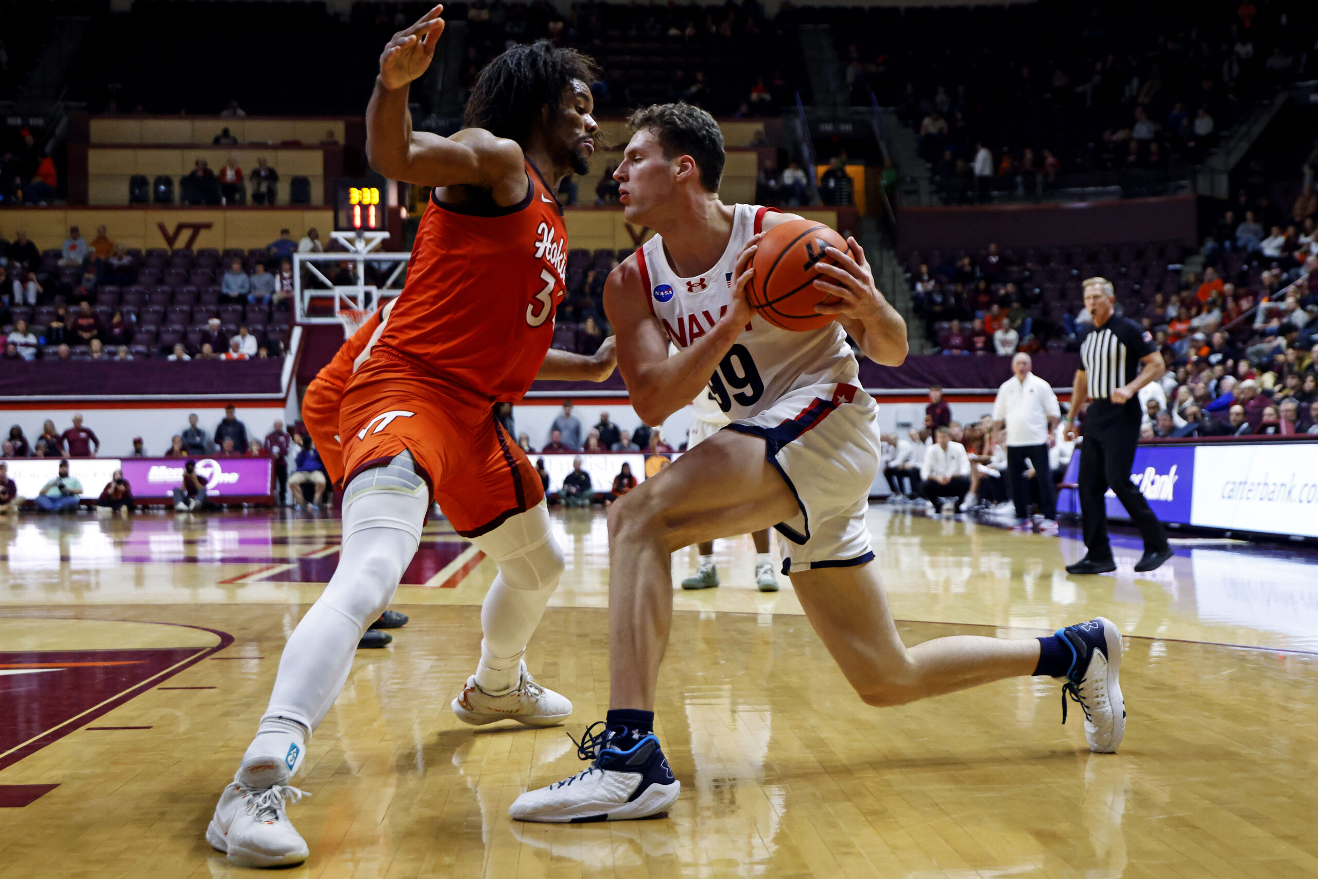Dec 15, 2024; Blacksburg, Virginia, USA; Navy Midshipmen center Aidan Kehoe (99) drives to the basket against Virginia Tech Hokies forward Mylyjael Poteat (34) during the second half at Cassell Coliseum. Mandatory Credit: Peter Casey-Imagn Images
