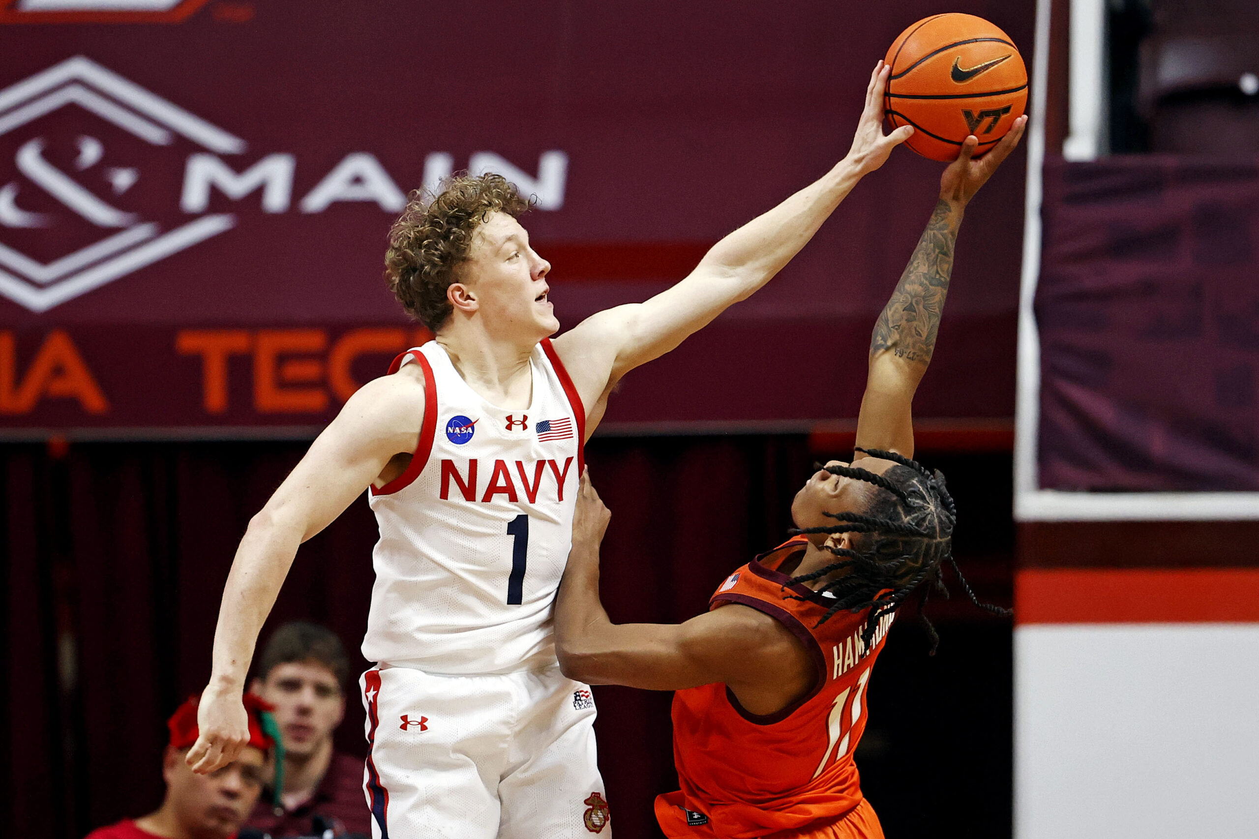 Dec 15, 2024; Blacksburg, Virginia, USA; Navy Midshipmen guard Austin Benigni (1) blocks the shot of Virginia Tech Hokies guard Ben Hammond (11) during the second half at Cassell Coliseum. Mandatory Credit: Peter Casey-Imagn Images