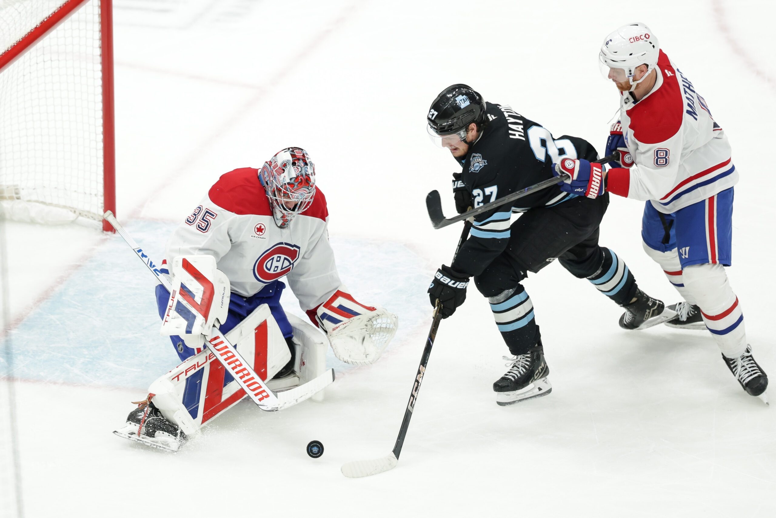 Jan 14, 2025; Salt Lake City, Utah, USA;  Utah Hockey Club center Barrett Hayton (27) tries to push the puck past Montreal Canadiens goaltender Sam Montembeault (35) during the second period at Delta Center. Mandatory Credit: Chris Nicoll-Imagn Images