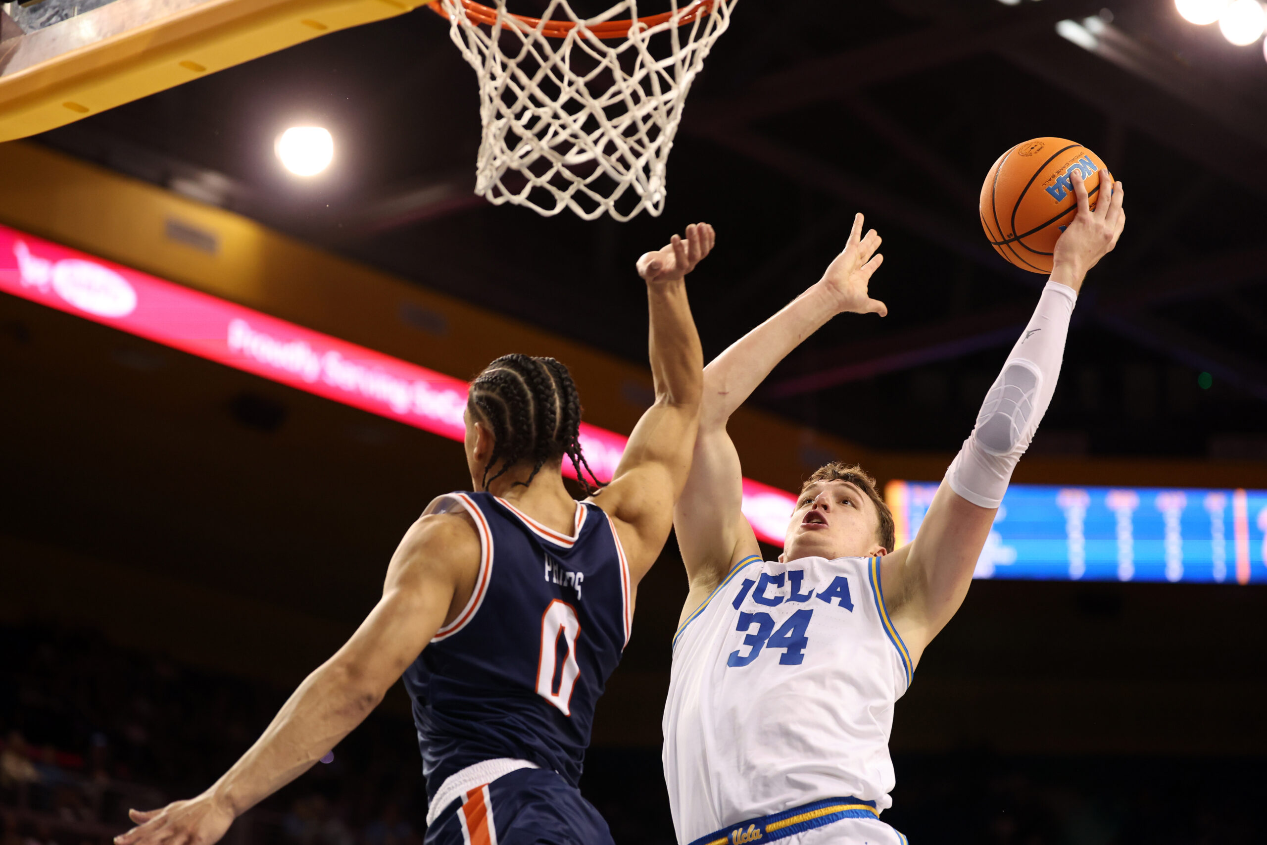 Nov 7, 2025; Los Angeles, California, USA;  UCLA Bruins forward Tyler Bilodeau (34) goes to the basket against Pepperdine Waves guard Styles Phipps (0) during the second half at Pauley Pavilion presented by Wescom Financial. Mandatory Credit: Kiyoshi Mio-Imagn Images