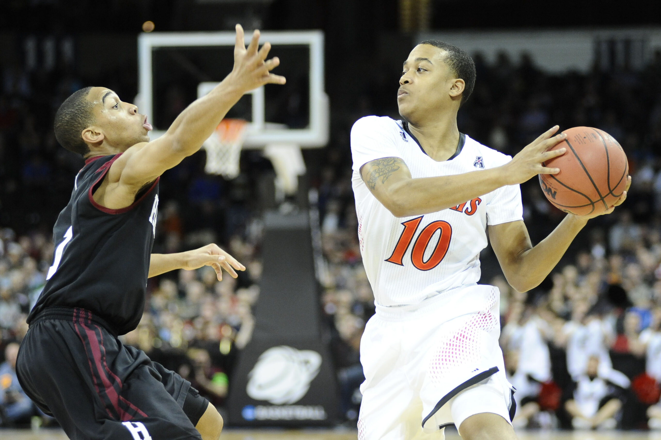Mar 20, 2014; Spokane, WA, USA; Cincinnati Bearcats guard Troy Caupain (10) is defended by Harvard Crimson guard Siyani Chambers (1, left) in the first half of a men's college basketball game during the second round of the 2014 NCAA Tournament at Veterans Memorial Arena. Mandatory Credit: James Snook-Imagn Images
